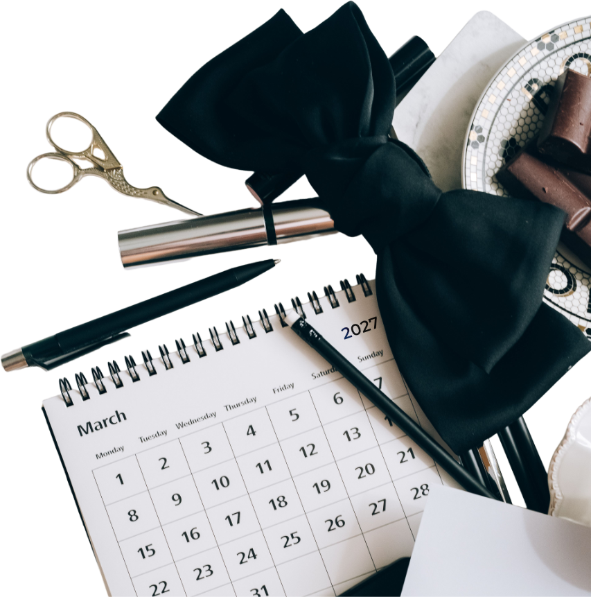 Kalender, Fliege, Schere und Stift auf einem Tisch